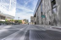 a city street with several tall buildings in the background, a man is driving on his motorcycle