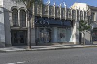 the store front of zara by a street with palm trees and building in the background