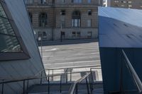 an angled view down from some stairs in the city of a city street with buildings in the background