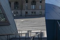 an angled view down from some stairs in the city of a city street with buildings in the background