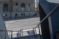 an angled view down from some stairs in the city of a city street with buildings in the background