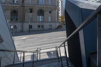 an angled view down from some stairs in the city of a city street with buildings in the background