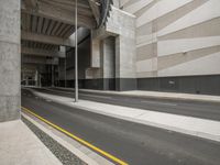 empty street next to a modern building with stone pillars and stairs on the side of the street