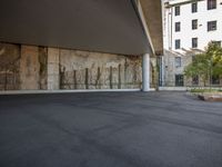 a man standing in an outdoor parking area with his skateboard up against a concrete wall