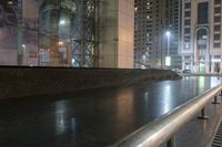 an empty bench outside of the building next to a sidewalk on a city street in the evening