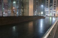 an empty bench outside of the building next to a sidewalk on a city street in the evening