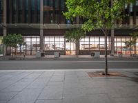 a building with trees and benches in front of it that are sitting on the pavement