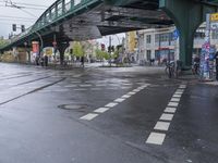 a city street with an overpass, bicycle and pedestrians and trams on the road