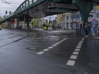 a city street with an overpass, bicycle and pedestrians and trams on the road