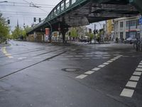 a city street with an overpass, bicycle and pedestrians and trams on the road