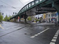 a city street with an overpass, bicycle and pedestrians and trams on the road