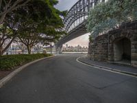 a city street under an overpass with a bridge in the background and trees to the side