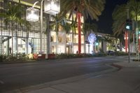 a city street with palm trees on both sides of the road and some buildings with lights at the top