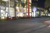 a city street with palm trees on both sides of the road and some buildings with lights at the top