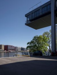 a car is parked in a parking lot near a bridge on the water's edge