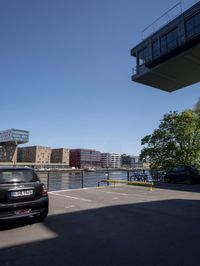 a car is parked in a parking lot near a bridge on the water's edge