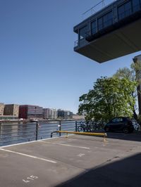 a car is parked in a parking lot near a bridge on the water's edge
