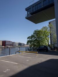 a car is parked in a parking lot near a bridge on the water's edge