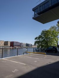 a car is parked in a parking lot near a bridge on the water's edge