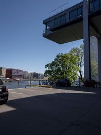 a car is parked in a parking lot near a bridge on the water's edge