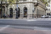 the corner of a street with people walking on it, and a car in the background