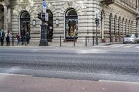 the corner of a street with people walking on it, and a car in the background