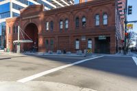a city street with a red brick building on the side of it and people walking across the street