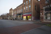 an empty street near an old brick building and a sign for the store on the side