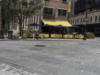 a restaurant with a yellow awning sitting in the middle of a city street area