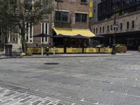 a restaurant with a yellow awning sitting in the middle of a city street area