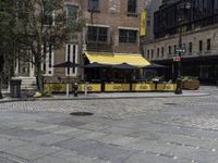 a restaurant with a yellow awning sitting in the middle of a city street area