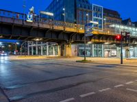 city street scene at dusk with traffic and pedestrian lights under pedestrian bridge over street intersection