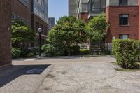 a sidewalk leading to some buildings and trees in a city street area by a park