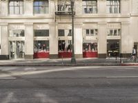 the street light stands alone at the intersection of the road as someone rides past the storefront