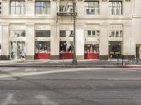 the street light stands alone at the intersection of the road as someone rides past the storefront