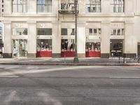 the street light stands alone at the intersection of the road as someone rides past the storefront