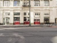the street light stands alone at the intersection of the road as someone rides past the storefront
