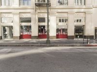 the street light stands alone at the intersection of the road as someone rides past the storefront