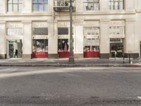 the street light stands alone at the intersection of the road as someone rides past the storefront