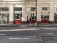 the street light stands alone at the intersection of the road as someone rides past the storefront