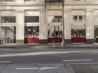 the street light stands alone at the intersection of the road as someone rides past the storefront