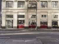 the street light stands alone at the intersection of the road as someone rides past the storefront