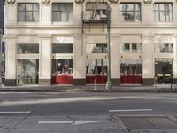 the street light stands alone at the intersection of the road as someone rides past the storefront