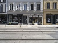 a store front next to a two car street with a bench in front of it