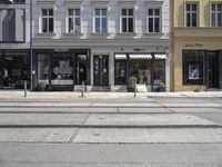 a store front next to a two car street with a bench in front of it