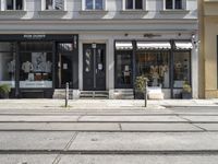 a store front next to a two car street with a bench in front of it