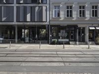 a store front next to a two car street with a bench in front of it