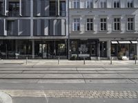 a store front next to a two car street with a bench in front of it