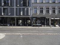 a store front next to a two car street with a bench in front of it