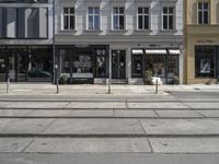 a store front next to a two car street with a bench in front of it